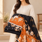 Woman holding the black and orange printed lawn unstitched fabric set.